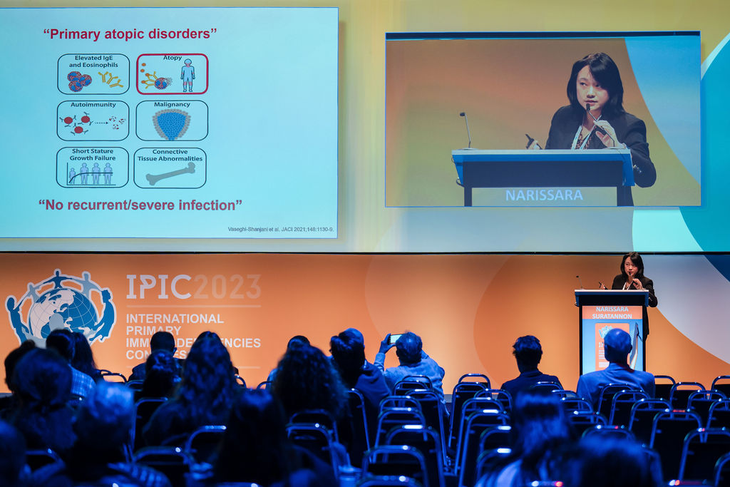 IPIC2023: A woman standing at a podium, presenting at a conference