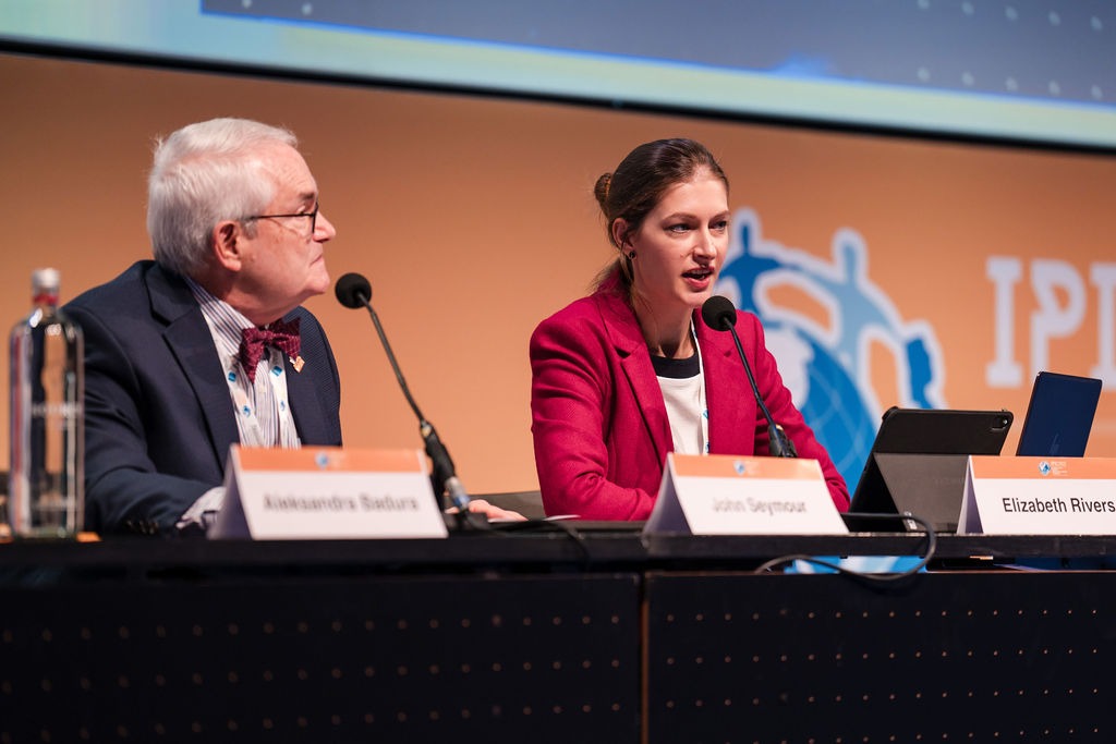 IPIC2023: Two people seated at a table, each with a microphone, engaged in discussion