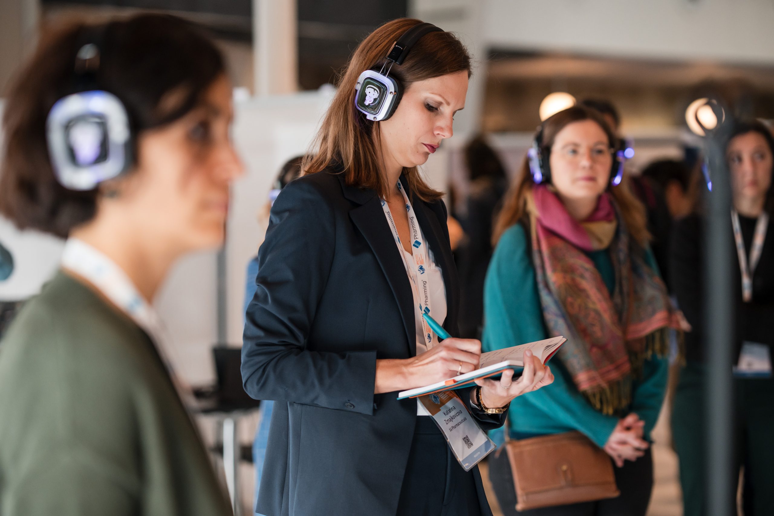 Sponsorship ProposalA woman wearing headphones takes notes, focused on a notepad in her hands_Sponsorship_ Proposal