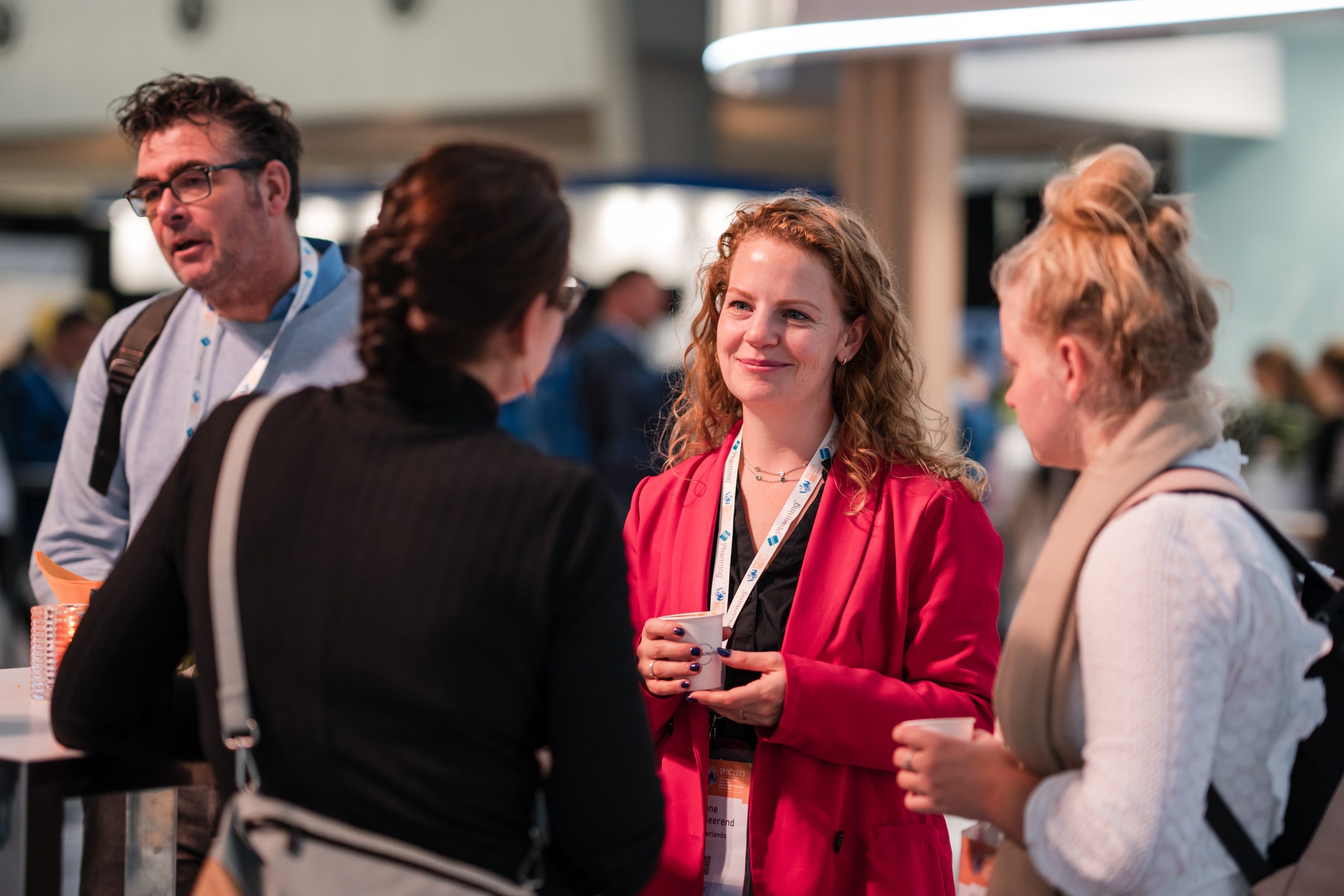 Sponsorship Proposal: 3 women engaged in conversation at a bustling event in a convention center setting.