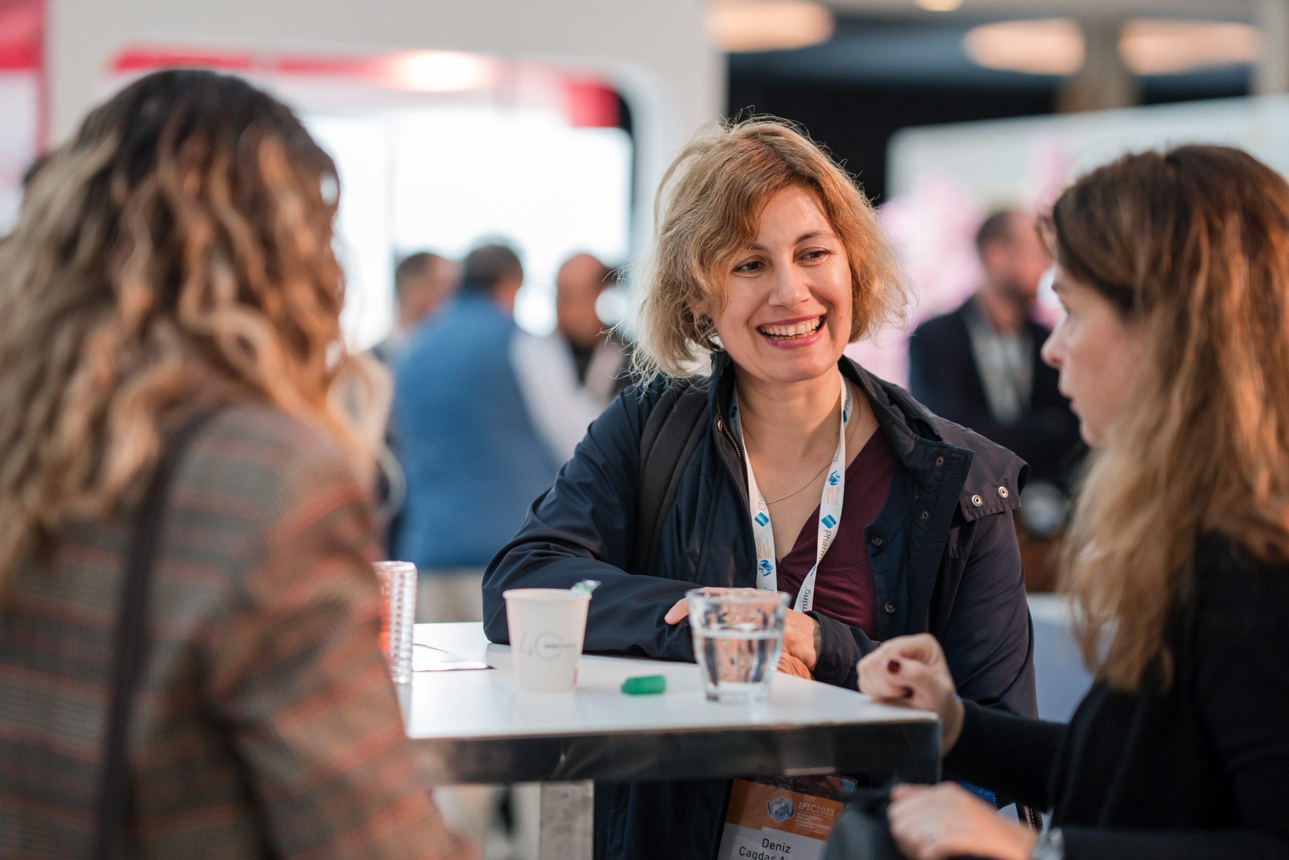 Sponsorship Proposal: A group of 3 women engaged in discussion around a conference table.